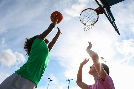 Two friends playing basketball. Both about 12 years old, African and Caucasian females.
