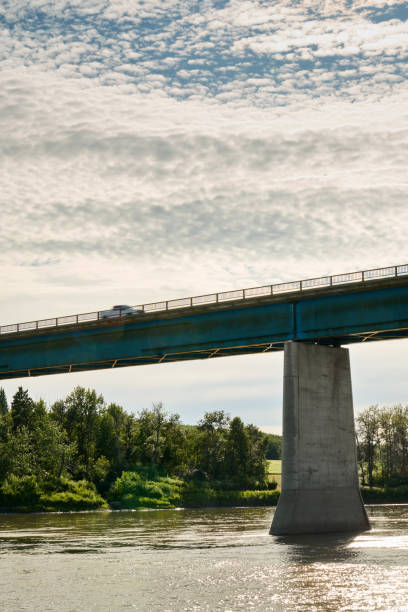 istock Pick-up truck driving on a bridge crossing over a river 1587936058
