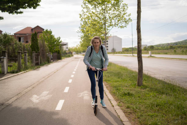 istock Young woman rides kick scooter down the street 1587946005