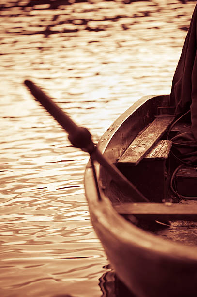 Resting little wood boat with oar in Lake Como at sunset.  Sepia tone added for the mood. The image is processed from 16 bit RAW files in sRGB colorspace.