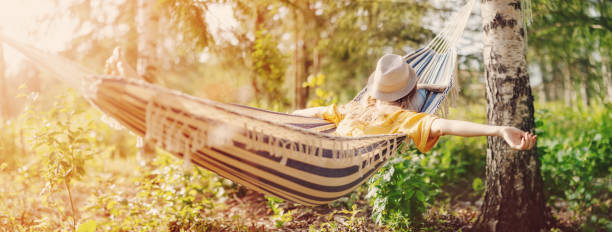 istock Woman lying in the hammock with hat on her face. 1587957424