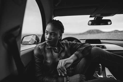 Beautiful black woman relaxing in the car. it's a rainy day outdoors.