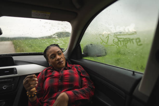 Beautiful black woman relaxing in the car. It's a rainy day outdoors.