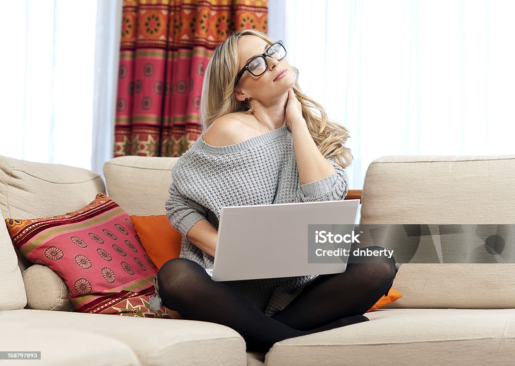 attractive woman with laptop having neck pain attractive woman with laptop in her home having a neck pain Neckache Stock Photo