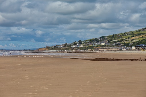 view from the beach to a hill with buildings and the sea in Barmouth, UK