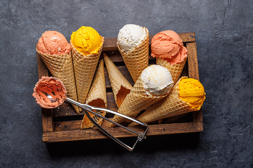 Assorted ice cream flavours in delightful waffle cones, a treat for every taste bud. Over stone background. Flat lay
