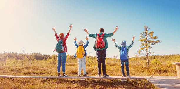 Family standing on the nature with rising hands.