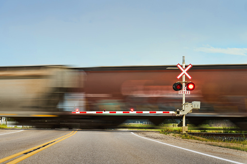Freight train traveling through a railroad crossing on a country road in blurred motion