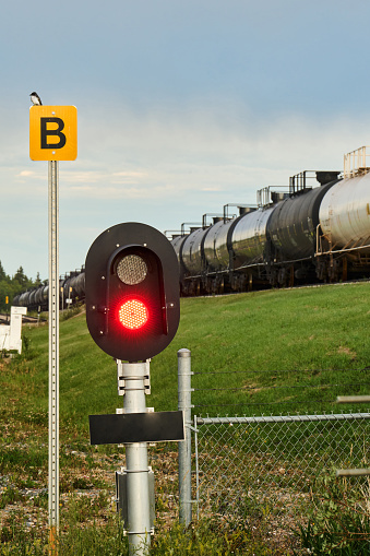 Freight train traveling by a a railroad crossing light on a country road on a late summer afternoon