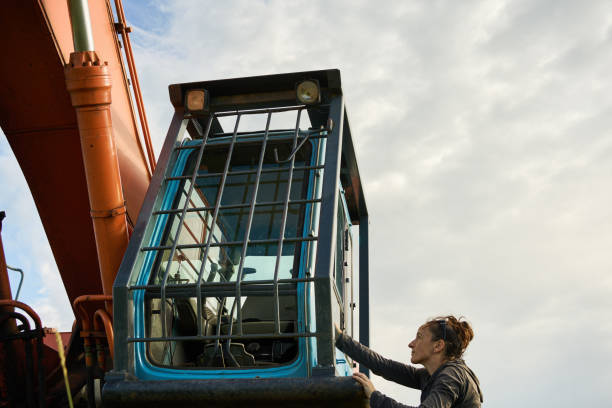 Young Building Worker is Sitting in the Cabin of a Large Construction Machine at eh Building SIte.