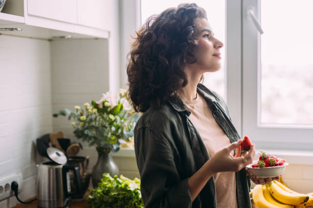 istock A Happy Beautiful Woman Looking Away While Eating Strawberries 1588090782
