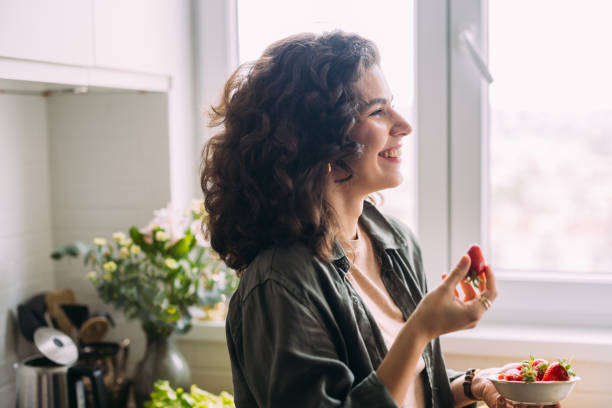 istock A Happy Beautiful Woman Looking Away While Eating Strawberries 1588090788