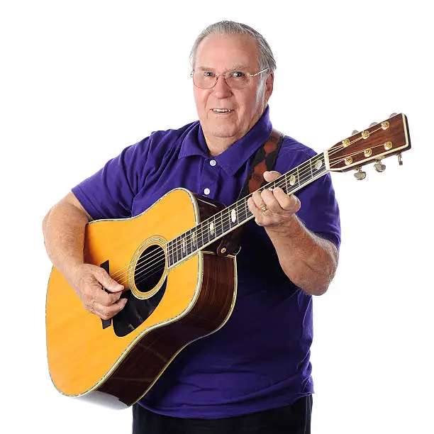 A happy senior man playing his guitar.  On a white background.