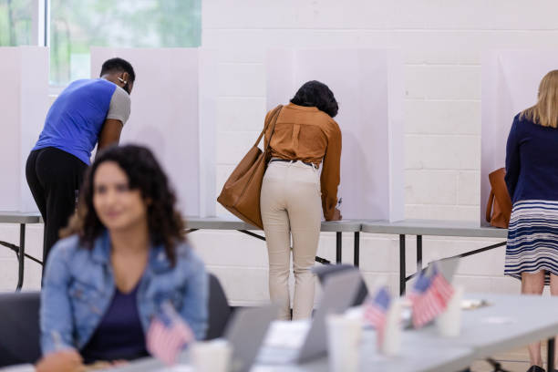 un groupe diversifié d’électeurs utilise des cloisons de confidentialité pour remplir leurs bulletins de vote - election presidential candidate usa bipartisan photos et images de collection