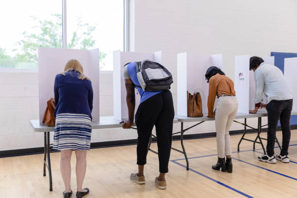 istock Diverse group of voters use privacy partitions to complete their ballots 1588098866