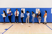 Diverse group of voters stand in line waiting to be assigned to a booth