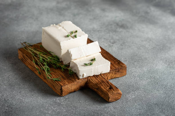 istock Feta cheese on a wooden board with thyme. Gray rustic background. Side view, selective focus. 1588106670