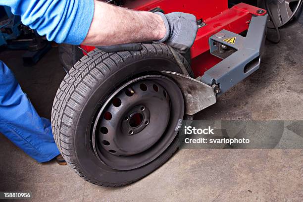 Mecánico A Tareas De Reparación A Tire En El Estacionamiento Foto de stock y más banco de imágenes de Adulto