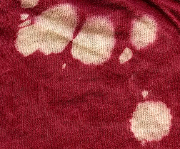 Photo of Red cotton fabric texture with numerous bleach stains