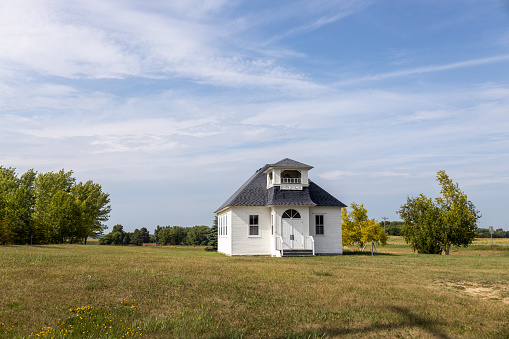 Cokato, Minnesota, USA - July 25, 2023: Landscape view of the Lee School, a one-room country schoolhouse which housed students in grades 1-8 from 1899 to 1971. It was moved from its original location in Wright County along the Crow River, to Temperance Corner in Cokato and restored in 1999.  It sits on the site of a previous country school that burned down.