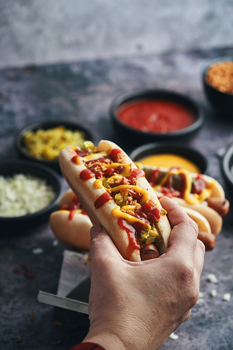 The photo depicts a mouthwatering assortment of Hot Dogs, each one customized with roasted onions, pickle relish and a variety of toppings.