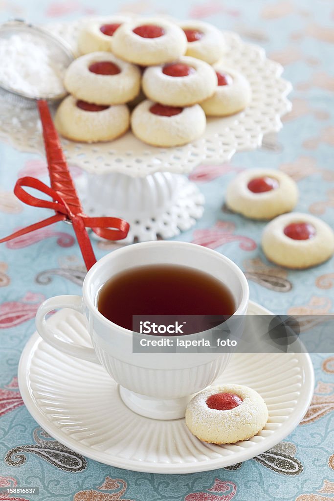 Cup of hot tea and homemade almond cookies Cup of hot tea and homemade almond cookies filled with jam, selective focus Blue Stock Photo