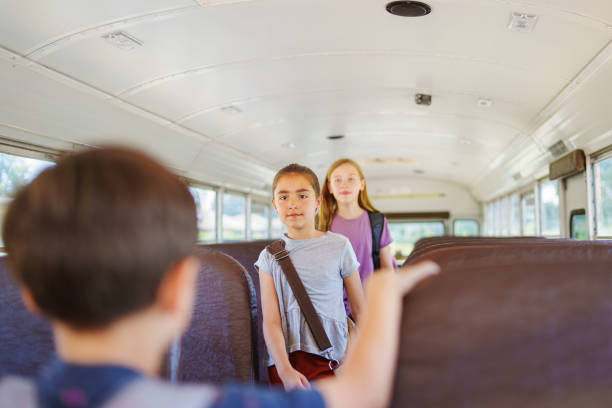 istock Elementary age girl walking down aisle of school bus 1588211384