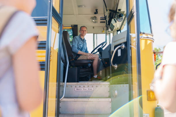 istock School bus driver at wheel while schoolchildren board bus. 1588211892