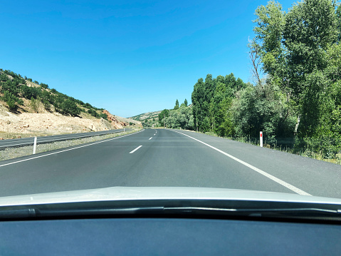 Driving on asphalt road on a sunny day. Car point of view empty asphalt road with clear sky background
