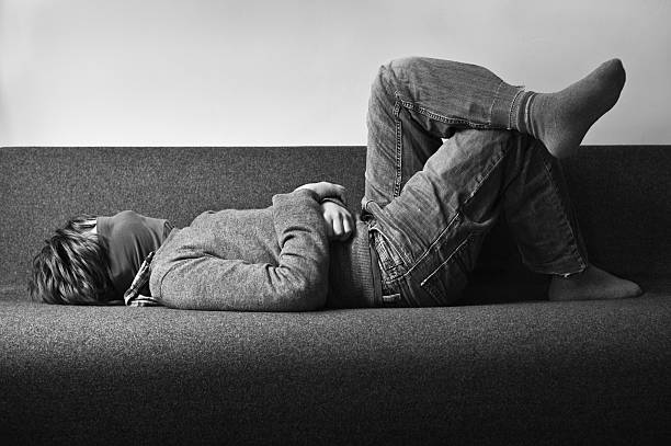 Child with covered face lying on the sofa stock photo