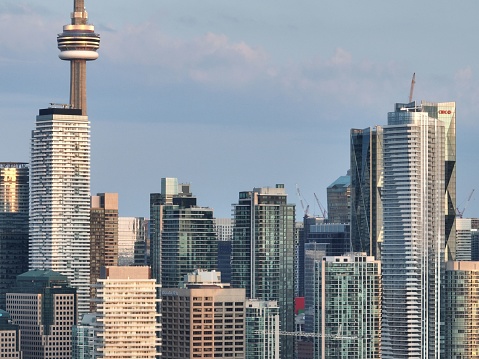 Toronto, Canada – July 23, 2023: Downtown Toronto at morning golden hour, building rooftops and a peak at the CN Tower, Toronto Star Building and construction cranes.