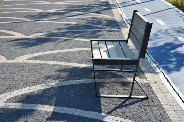 Empty park bench with cobblestone flooring in public park