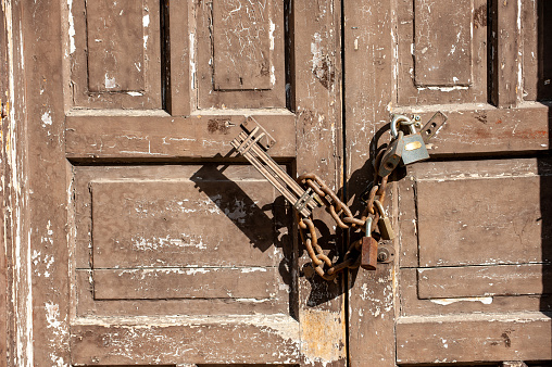 Old steel door lock on an old battered door, close-up.