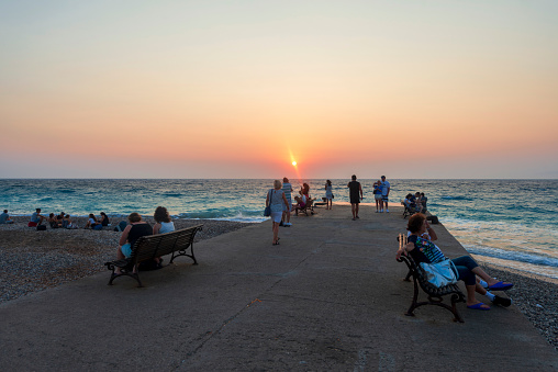 Tourists watching the sunset on the pier near New Town in Rhodes island. Rhodes, Greece. August.01.2016