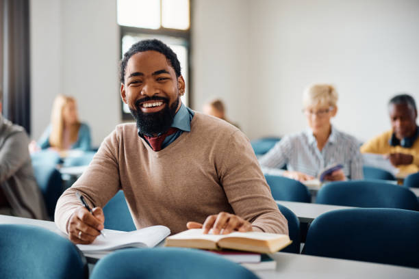 istock Happy black man taking notes while studying in the classroom and looking at camera. 1588286305