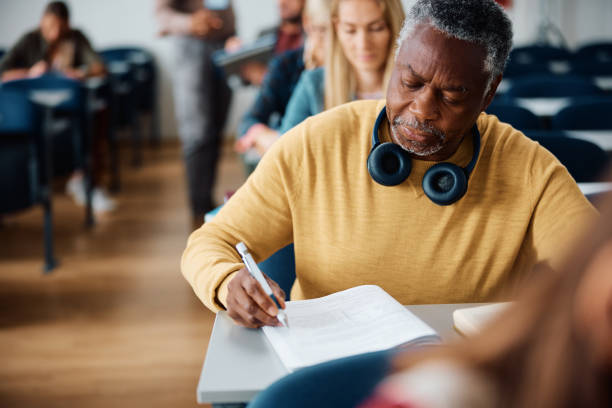 istock Black senior man writing educational exam in the classroom. 1588287352