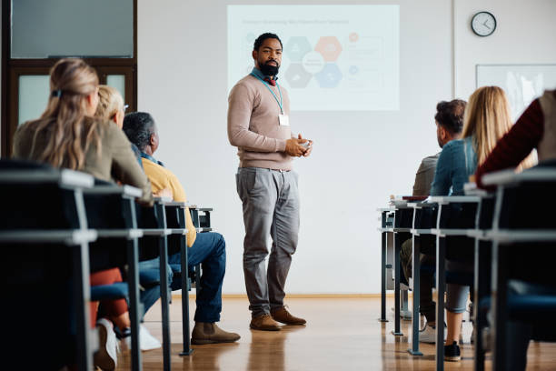 Black adult education teacher giving presentation in the classroom. African American professor teaching group of adult students during educational course in lecture hall. teacher projector stock pictures, royalty-free photos & images