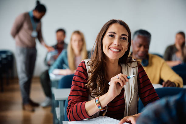 istock Happy female student attending a class in lecture hall. 1588287867