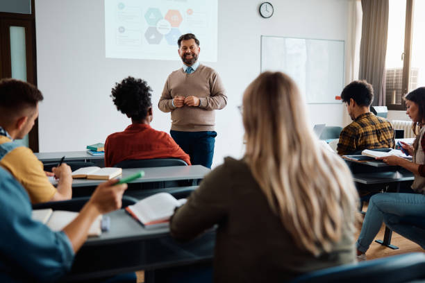 istock Happy mature teacher talking to his students while holding a presentation in lecture hall. 1588288920
