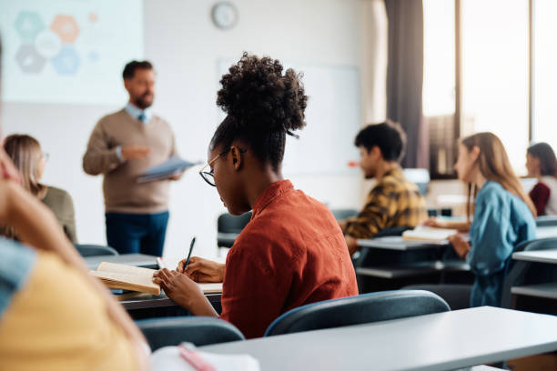 estudiante negra tomando notas durante una clase en la sala de conferencias. - sala de conferencias fotografías e imágenes de stock