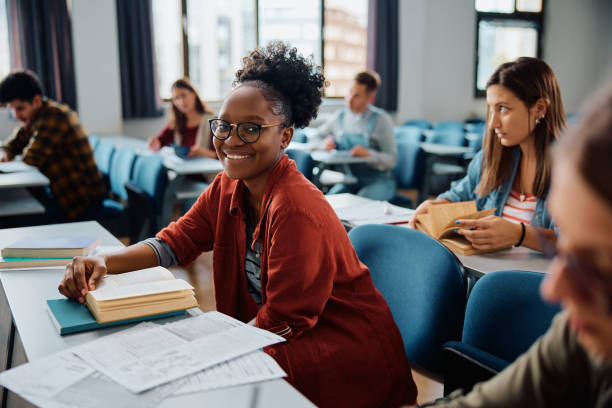 istock Happy black woman studying during a class in lecture hall and looking at camera. 1588290517