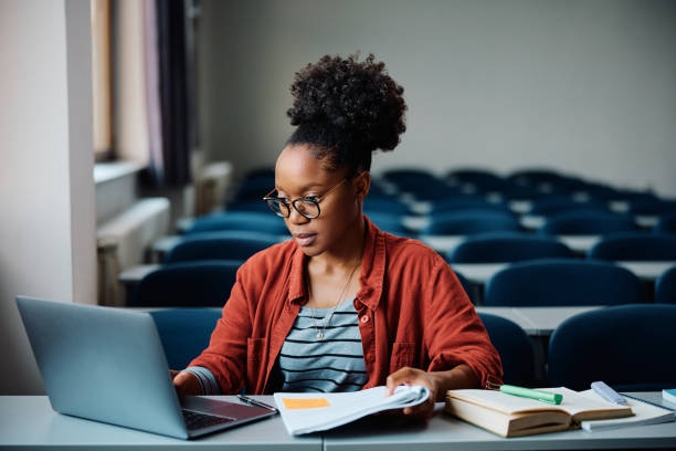 istock Black female student e-learning on laptop in lecture hall. 1588291032