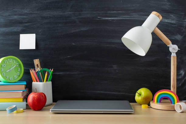 istock Achieve academic success with this student's study environment. Side view shot of laptop and office supplies on wooden desk on chalkboard isolated backdrop, offering copy-space for text or advertising 1588317004