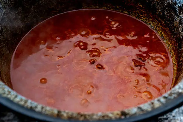 Photo of Traditional goulash soup is cooking in the a cauldron.