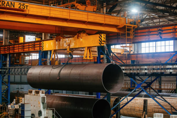istock Finished pipe transportation by overhead crane in pipe factory 1588388965