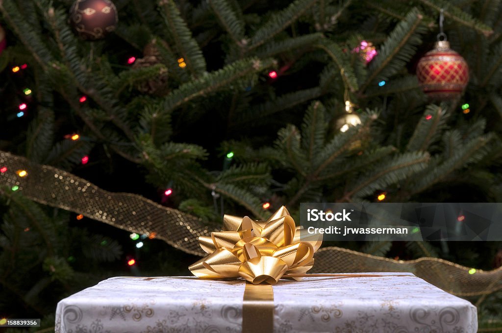 Presente de Natal com tigela de ouro em frente a árvore - Foto de stock de Bola de Árvore de Natal royalty-free