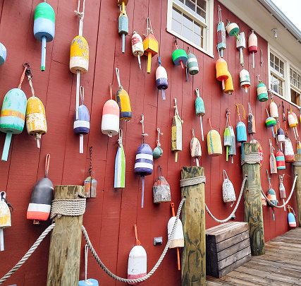 Old, colorful lobster buoys on side of fishing shack wall in Bar Harbor, Maine.