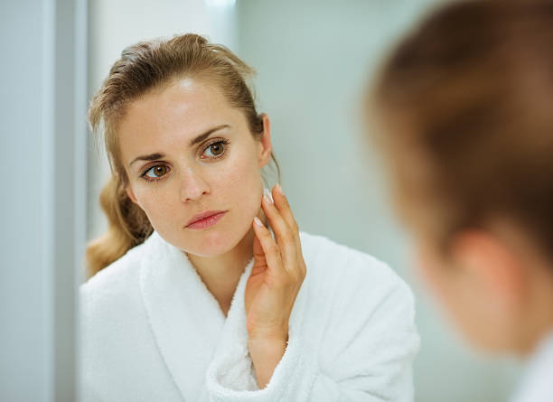istock Young woman checking her face in mirror 158844788