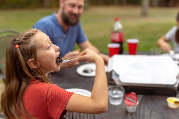 istock Young girl eats dessert as father watches in backyard 1588478783
