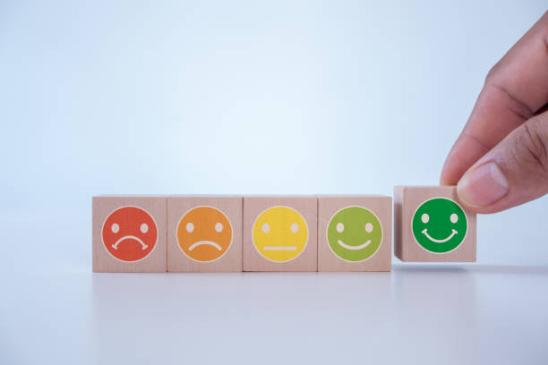 istock Customer service evaluation and satisfaction survey concepts. The client's hand picked the happy face smile face icon on wooden cube block on white background. copy space. 1588482938